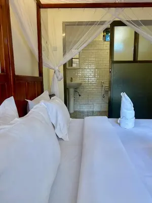 a bedroom with two beds with white pillows at Patamu Restaurants Lodge & Safaris in Karatu