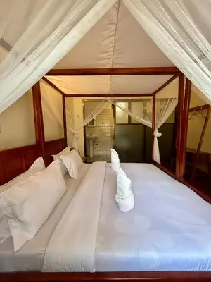 a large white bed with a canopy in a room at Patamu Restaurants Lodge & Safaris in Karatu