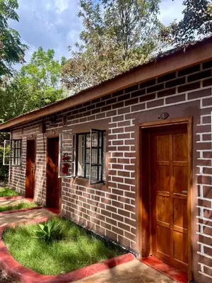 a brick house with a wooden door and a yard at Patamu Restaurants Lodge & Safaris in Karatu