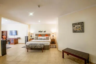 a bedroom with a bed and a bench in it at African Tulip Hotel in Arusha