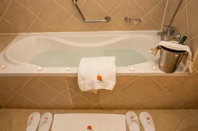 a bath tub with a towel and a trash can at African Tulip Hotel in Arusha