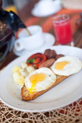 a plate of eggs and bread on a table at African Tulip Hotel in Arusha
