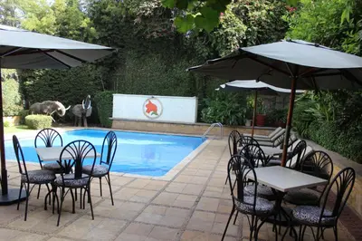 a table and chairs with umbrellas next to a pool at African Tulip Hotel in Arusha