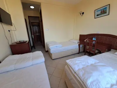 a hotel room with two beds and a desk at Moshi Leopard Hotel in Moshi