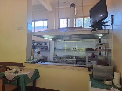 a kitchen with a person working in a kitchen at Moshi Leopard Hotel in Moshi
