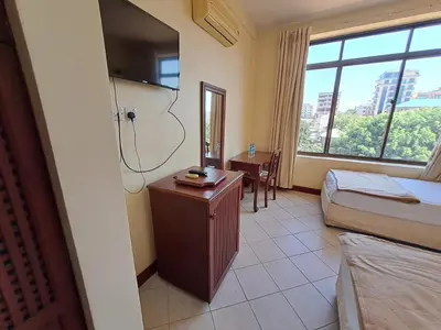 a hotel room with a bed and a desk and a window at Moshi Leopard Hotel in Moshi
