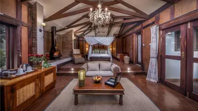 a living room with a bed and a chandelier at Elewana Arusha Coffee Lodge in Arusha