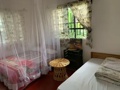 a bedroom with two beds and a window with curtains at Tamaduni Homestay & Lodge in Arusha
