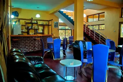 a restaurant with blue chairs and tables and stairs at NGORONGORO CORRIDOR LODGE Karatu in Karatu