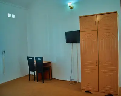 a room with two chairs and a cabinet and a table at NGORONGORO CORRIDOR LODGE Karatu in Karatu