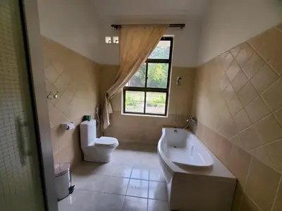 a bathroom with a sink and a toilet and a window at NGORONGORO CORRIDOR LODGE Karatu in Karatu