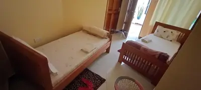 a small room with two beds and a chair at Kilimanjaro Budget Lodge in Msaranga