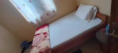 a small bed in a small room with a window at Kilimanjaro Budget Lodge in Msaranga