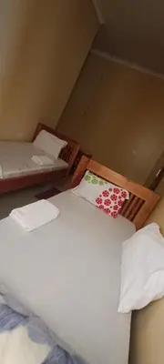 a bedroom with two beds with white sheets at Kilimanjaro Budget Lodge in Msaranga