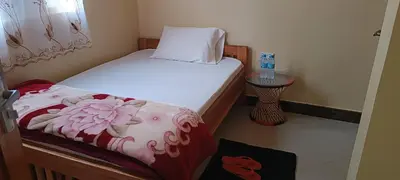a small bedroom with a bed with a white bedspread with flowers at Kilimanjaro Budget Lodge in Msaranga