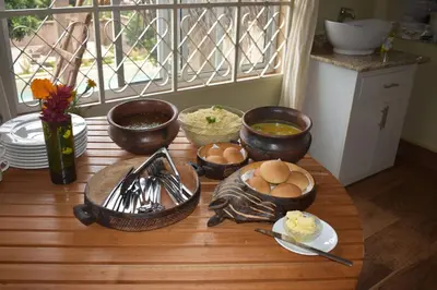 a table with bowls and plates of food on it at Kili Kivuli in Msaranga