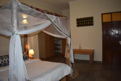 a bedroom with a canopy bed and a table at Kili Kivuli in Msaranga
