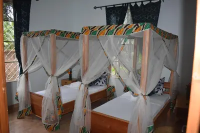 a bedroom with a four poster bed with mosquito nets at Kili Kivuli in Msaranga