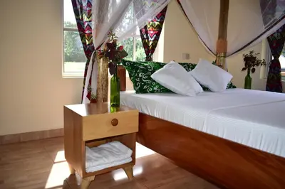 a bedroom with a bed and a table with a night stand at Kili Kivuli in Msaranga