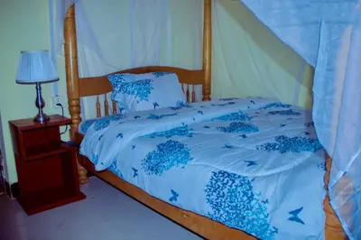 a bed with a blue comforter and pillows on it at Biez Homestay in Karatu