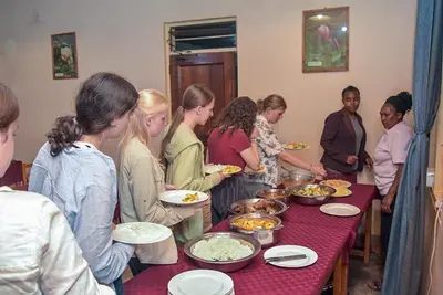 a group of people standing around a table with food at Biez Homestay in Karatu
