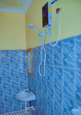 a blue tiled bathroom with a shower and a sink at Biez Homestay in Karatu
