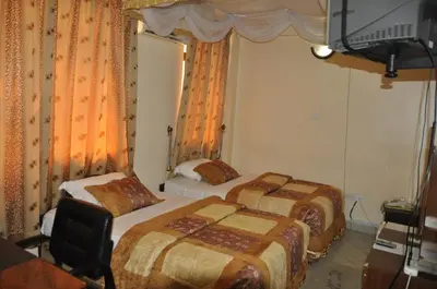 a hotel room with two beds and a television at Rich Hotel in Arusha