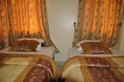 two beds in a room with orange curtains at Rich Hotel in Arusha