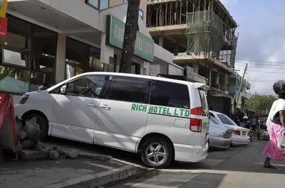 a white van parked in front of a building at Rich Hotel in Arusha
