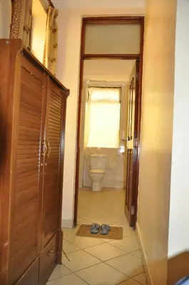a bathroom with a toilet and a pair of shoes on the floor at Rich Hotel in Arusha