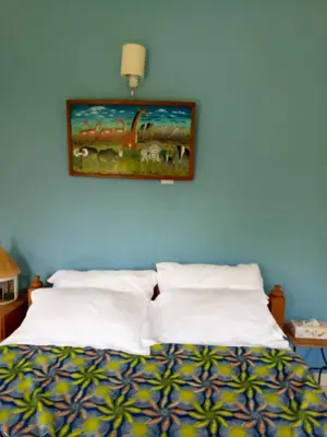 a bedroom with a bed with a painting on the wall at Kilimanjaro Eco Lodge in Usa River