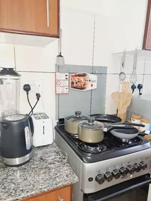 a kitchen with a stove with pots and pans on it at Logic Stays 2 Bedroom Arusha City Centre in Arusha