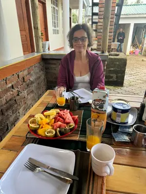 a woman sitting at a table with a plate of food at Seven Seven B&B in Arusha