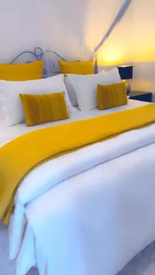 a bed with yellow and white pillows on it at Amala villas in Arusha