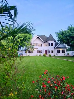 a large white house with a yard with red flowers at Amala villas in Arusha