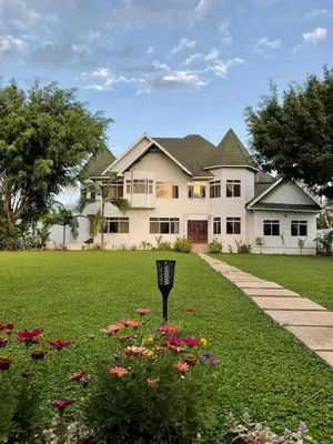 a large white house with flowers in the yard at Amala villas in Arusha