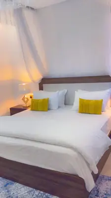 a large white bed with two yellow pillows at Amala villas in Arusha