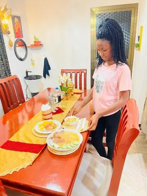 a woman standing next to a table with a cake at KILIMANJARO HOME OF RASON in Msaranga