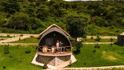 a man standing inside of a thatch roof house at Africa Safari Rift Valley in Magara