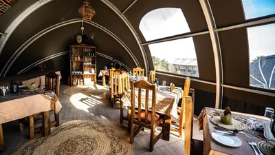 a dining room with tables and chairs and windows at Africa Safari Rift Valley in Magara