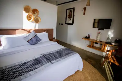 a bedroom with a large white bed with a television at The Maridadi Hotel in Moshi