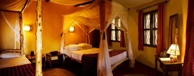 a bedroom with a canopy bed and two windows at NSYA CAMP MANYARA in Mto wa Mbu