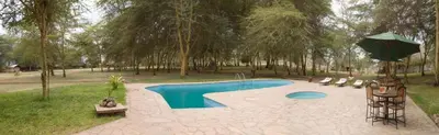 a swimming pool with an umbrella in a park at NSYA CAMP MANYARA in Mto wa Mbu