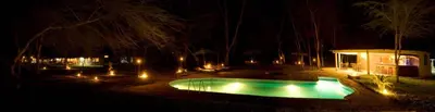a pool with lights in a yard at night at NSYA CAMP MANYARA in Mto wa Mbu