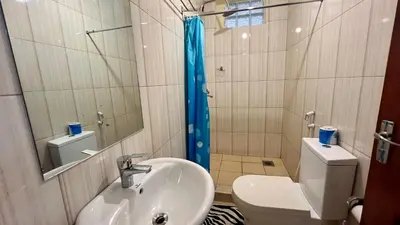 a bathroom with a sink and a toilet and a mirror at Runako Hostel in Arusha