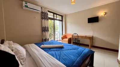 a bedroom with a bed and a desk and a window at Runako Hostel in Arusha