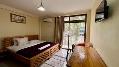 a bedroom with a bed and a window and a chair at Runako Hostel in Arusha