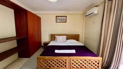 a small bedroom with a bed with a purple blanket at Runako Hostel in Arusha