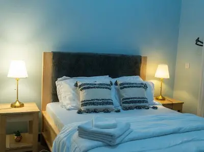 a blue bed with towels on it with two lamps at ILBORU HAVEN HOMEs in Arusha