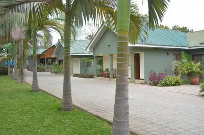 a group of palm trees in front of a house at Destination 3Degrees Hotel in Arusha